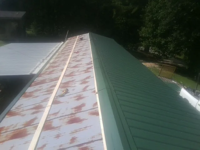 Old rusted panels beside newly installed green metal roofing — Wind Damage Roof Repair by Roofing Brothers in Sundance