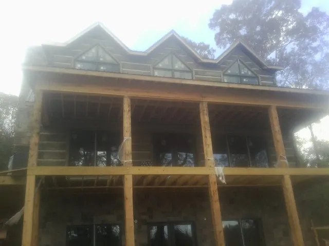 Dormers and porch framing on a large log home under construction — Roof Coating work by our crew in Sundance