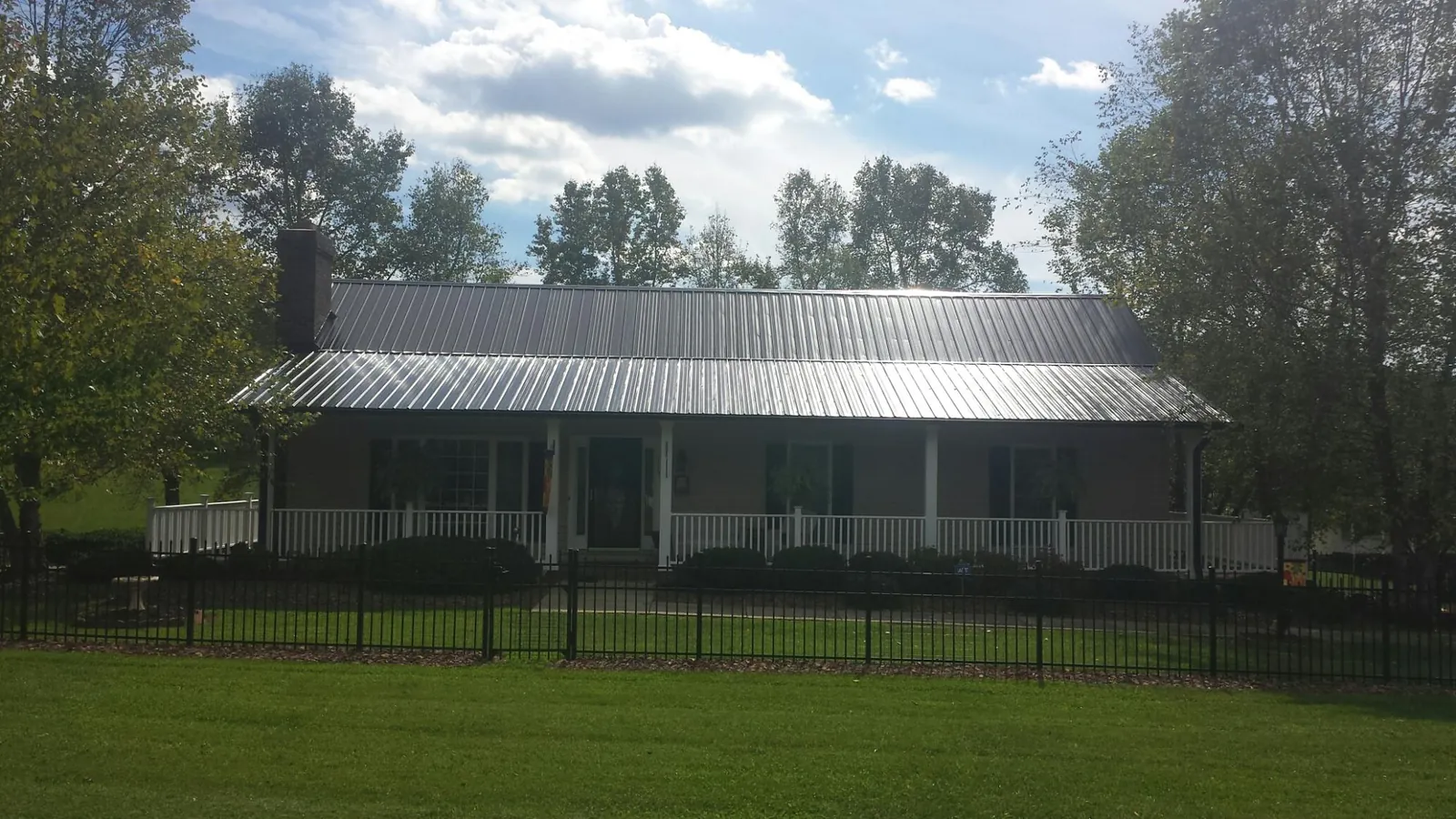 Gray metal roof on a brick ranch with a full width front porch — Gutter Guard Installation work by our crew in Sundance