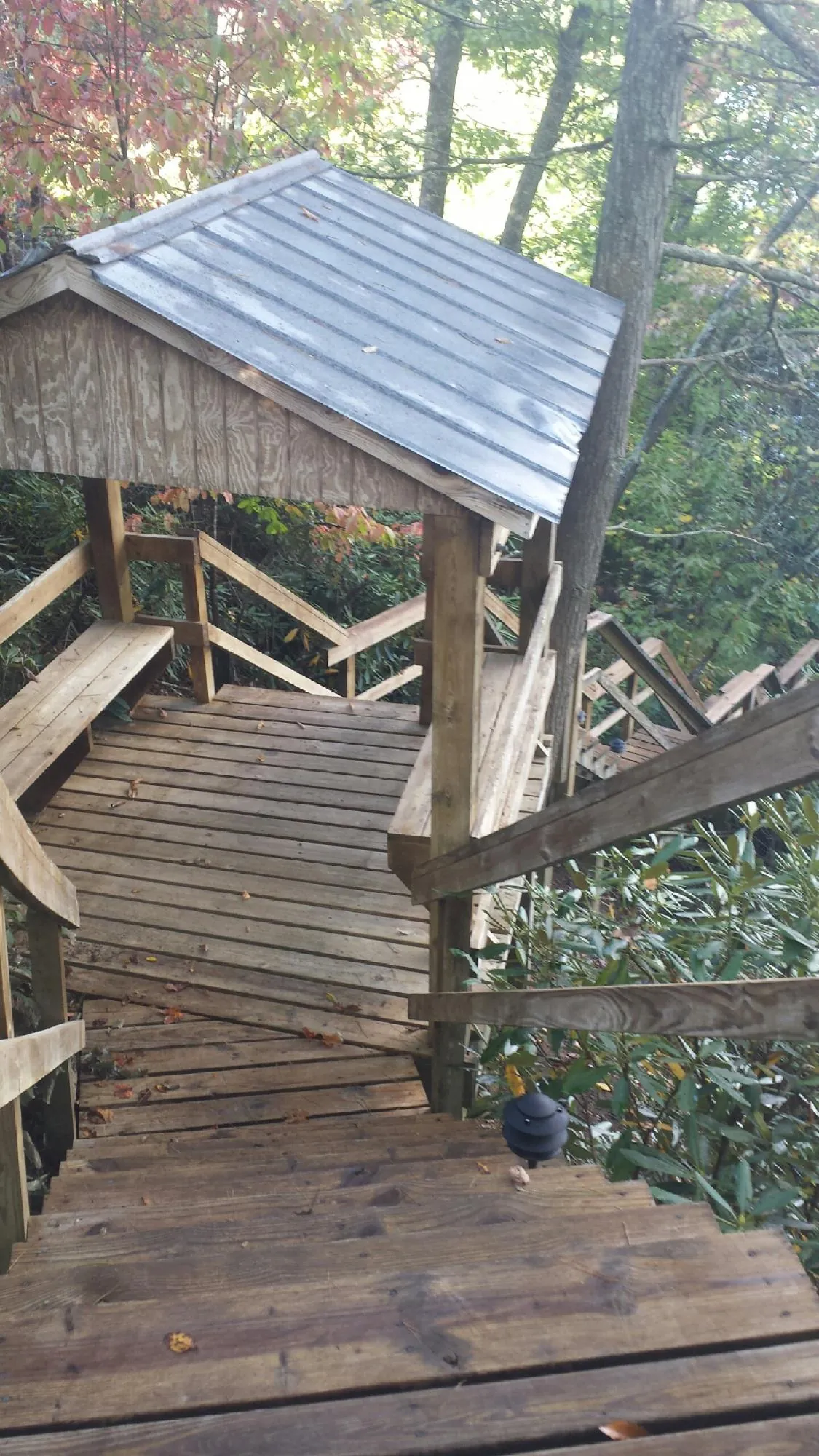 Metal roofed shelter over wooden steps on a wooded walkway — Skylight Repair & Installation work by our crew in Sundance