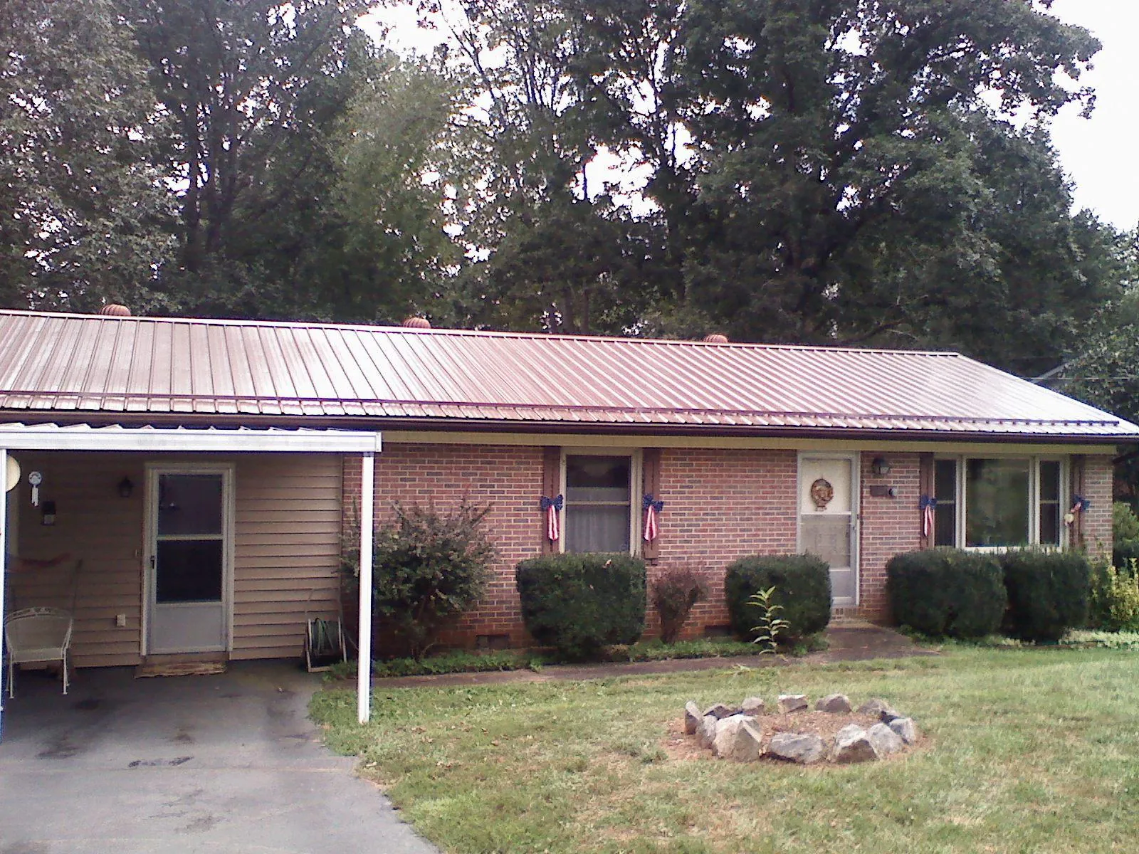 Bronze metal roof and carport on a brick ranch home — Roof Repair work by our crew in Sundance