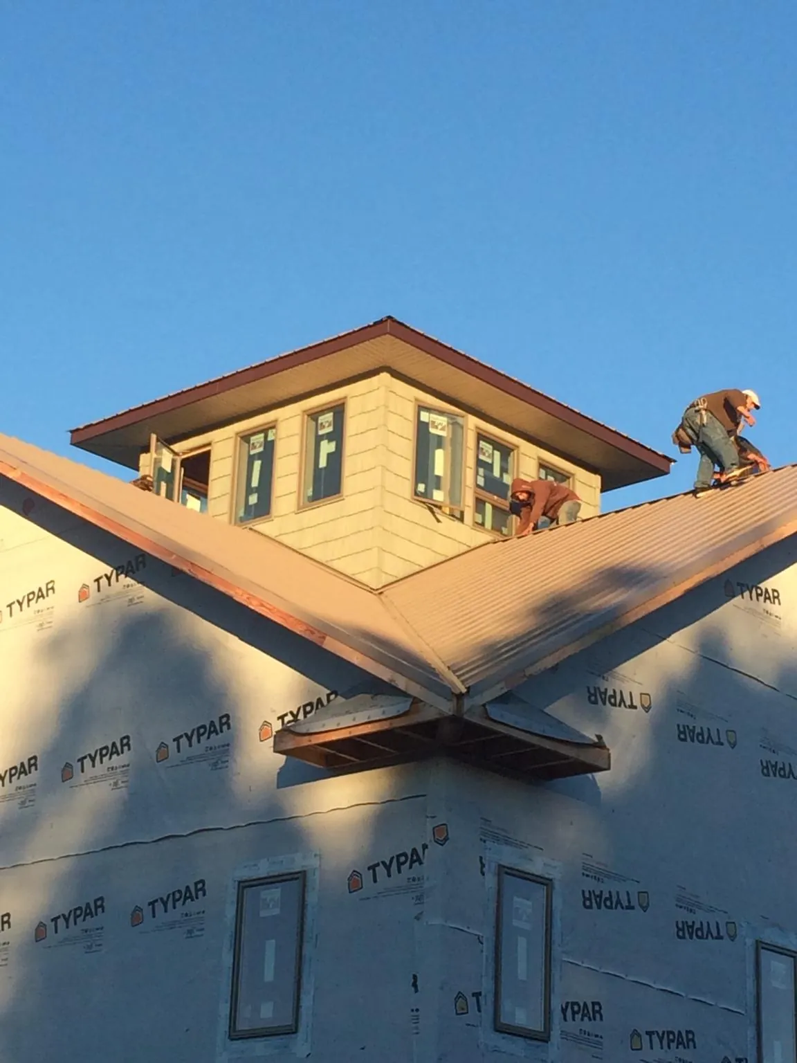 Roofers working around a rooftop cupola on a new metal roof at sunset — Roof Waterproofing in Sundance by Roofing Brothers